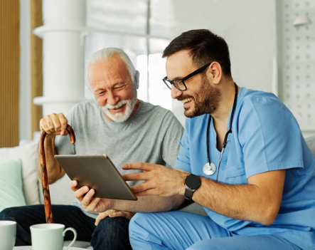 Doctor or nurse caregiver showing a tablet screen to senior man